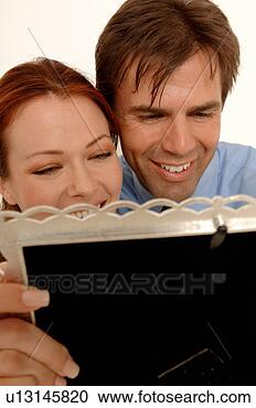 Stock Photography - an attractive 
couple enjoy themselves 
looking at photographs 
in frames. fotosearch 
- search stock 
photos, pictures, 
images, and photo 
clipart