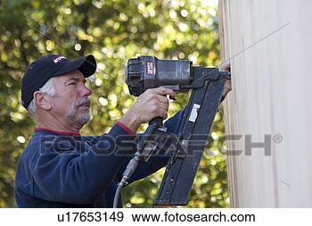 Stock Photograph - carpenter shooting 
nails into plywood 
with nail gun 
at construction. 
fotosearch - search 
stock photos, 
pictures, images, 
and photo clipart