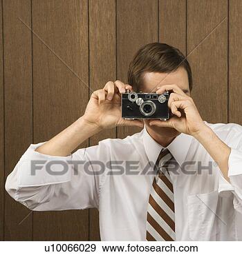 Stock Photograph - mid-adult caucasian 
male holding vintage 
camera up to his 
face. fotosearch 
- search stock 
photos, pictures, 
images, and photo 
clipart