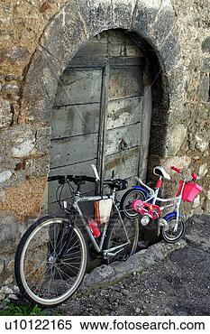 Stock Image - adult and childs 
bikes chained 
to old arched 
wooden door. fotosearch 
- search stock 
photos, pictures, 
images, and photo 
clipart