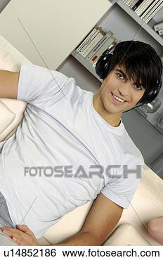 Stock Photo - young man on sofa 
listening to music 
with headphones. 
fotosearch - search 
stock photos, 
pictures, images, 
and photo clipart
