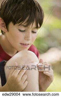 Stock Photo - boy putting bandage 
over knee scrape. 
fotosearch - search 
stock photos, 
pictures, images, 
and photo clipart