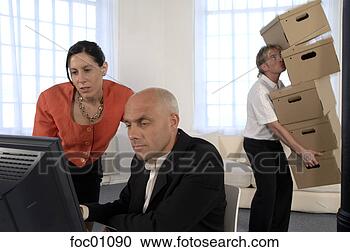Stock Photography - businessman working 
while co-worker 
carries moving 
boxes. fotosearch 
- search stock 
photos, pictures, 
images, and photo 
clipart