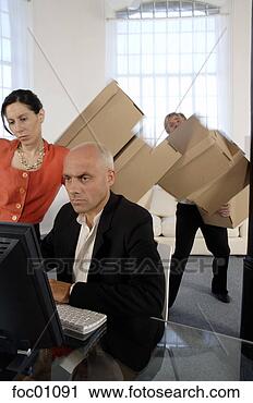 Stock Photography - businessman working 
while co-worker 
drops moving boxes. 
fotosearch - search 
stock photos, 
pictures, images, 
and photo clipart