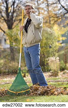 Stock Photo - man holding rake 
and talking on 
cell phone in 
yard. fotosearch 
- search stock 
photos, pictures, 
images, and photo 
clipart