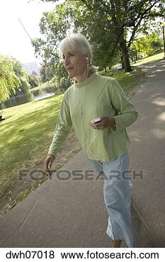 Stock Photo - senior woman walking 
holding mp3 player 
in park. fotosearch 
- search stock 
photos, pictures, 
images, and photo 
clipart