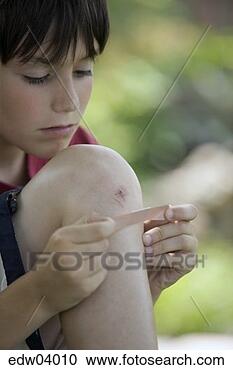 Stock Photography - young boy putting 
bandage on knee. 
fotosearch - search 
stock photos, 
pictures, images, 
and photo clipart