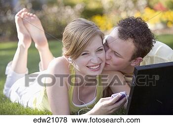 Stock Photo - young man kissing 
girlfriend while 
she listens to 
music. fotosearch 
- search stock 
photos, pictures, 
images, and photo 
clipart
