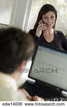 Stock Photo - young man using 
laptop as wife 
talks on cell 
phone. fotosearch 
- search stock 
photos, pictures, 
images, and photo 
clipart
