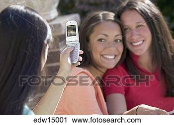 Stock Photography - young woman taking 
picture of friends 
with camera phone. 
fotosearch - search 
stock photos, 
pictures, images, 
and photo clipart