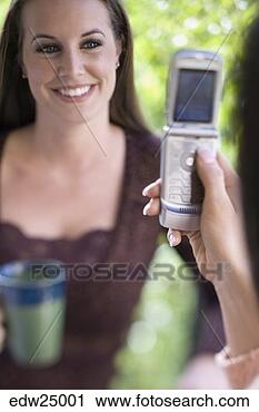 Stock Photography - young woman taking 
picture of friend 
with camera phone. 
fotosearch - search 
stock photos, 
pictures, images, 
and photo clipart