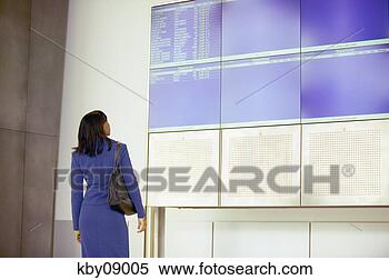 Stock Image - african businesswoman 
examining departures 
and arrivals board 
in. fotosearch 
- search stock 
photos, pictures, 
images, and photo 
clipart