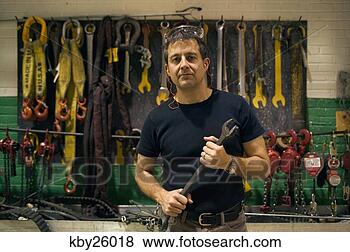 Stock Photo - man holding wrench 
in workshop. fotosearch 
- search stock 
photos, pictures, 
images, and photo 
clipart