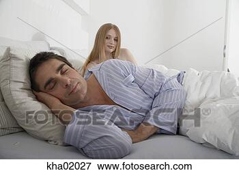 Picture - man sleeping in 
bed with wife 
looking over his 
shoulder. fotosearch 
- search stock 
photos, pictures, 
images, and photo 
clipart