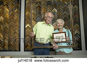 Stock Photo - senior couple 
holding frame 
in frame shop. 
fotosearch - search 
stock photos, 
pictures, images, 
and photo clipart