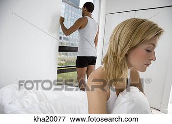 Picture - woman looking 
out window with 
back turned to 
man on bed. fotosearch 
- search stock 
photos, pictures, 
images, and photo 
clipart