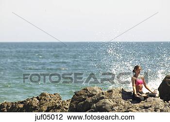 Stock Photo - woman sitting 
cross-legged on 
rocky beach. fotosearch 
- search stock 
photos, pictures, 
images, and photo 
clipart