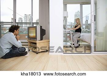 Stock Photo - woman working 
at computer as 
boyfriend is watching 
television. fotosearch 
- search stock 
photos, pictures, 
images, and photo 
clipart