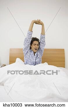 Stock Photo - young hispanic 
man sitting in 
bed stretching. 
fotosearch - search 
stock photos, 
pictures, images, 
and photo clipart