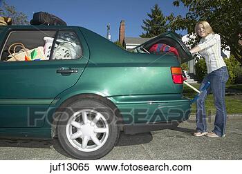 Stock Image - young woman cramming 
car trunk. fotosearch 
- search stock 
photos, pictures, 
images, and photo 
clipart