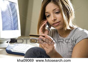 Stock Photograph - young woman with 
credit card talking 
on cell phone 
by desktop computer. 
fotosearch - search 
stock photos, 
pictures, images, 
and photo clipart
