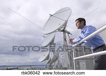 Stock Photo - businessman leaning 
on balcony near 
satellite dishes. 
fotosearch - search 
stock photos, 
pictures, images, 
and photo clipart