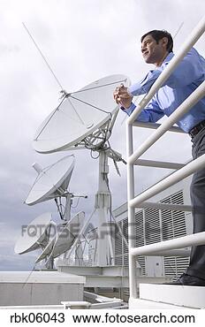 Stock Photo - businessman leaning 
on balcony near 
satellite dishes. 
fotosearch - search 
stock photos, 
pictures, images, 
and photo clipart