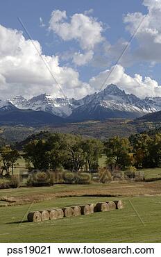 Stock Photography - hayrolls in countryside, 
rocky mountains. 
fotosearch - search 
stock photos, 
pictures, images, 
and photo clipart