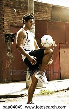 Stock Photograph - hispanic man kneeing 
soccer ball on 
urban street. 
fotosearch - search 
stock photos, 
pictures, images, 
and photo clipart
