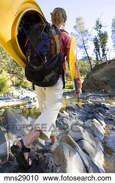 Stock Photography - rear view of woman 
carrying kayak 
across craggy 
stream. fotosearch 
- search stock 
photos, pictures, 
images, and photo 
clipart