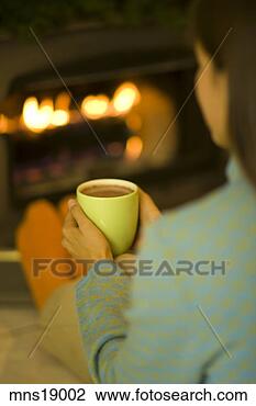 Stock Photo - woman holding 
mug by fireplace. 
fotosearch - search 
stock photos, 
pictures, images, 
and photo clipart