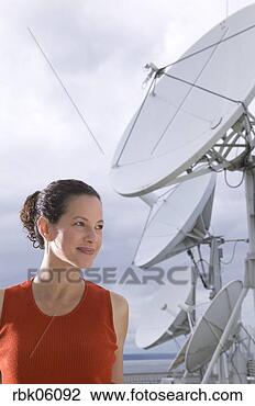 Stock Photo - woman standing 
near large satellite 
dish. fotosearch 
- search stock 
photos, pictures, 
images, and photo 
clipart