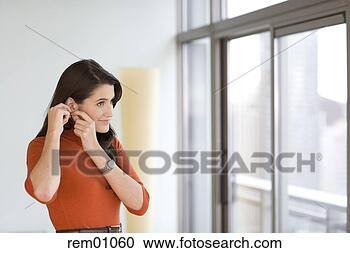 Stock Photography - young adult woman 
putting on earrings. 
fotosearch - search 
stock photos, 
pictures, images, 
and photo clipart