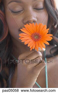 Stock Photo - young african 
woman smelling 
flower. fotosearch 
- search stock 
photos, pictures, 
images, and photo 
clipart