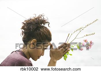 Stock Photo - young asian woman 
praying and holding 
flowers. fotosearch 
- search stock 
photos, pictures, 
images, and photo 
clipart