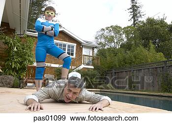 Stock Photograph - young boy in superhero 
costume stepping 
on his father's 
back. fotosearch 
- search stock 
photos, pictures, 
images, and photo 
clipart