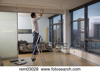 Stock Photo - young man replacing 
light bulb. fotosearch 
- search stock 
photos, pictures, 
images, and photo 
clipart
