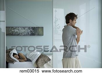 Stock Image - young man stretching 
as girlfriend 
sleeps. fotosearch 
- search stock 
photos, pictures, 
images, and photo 
clipart