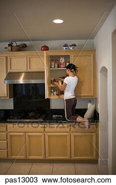 Stock Photo - young woman kneeling 
on counter to 
look through cabinet. 
fotosearch - search 
stock photos, 
pictures, images, 
and photo clipart