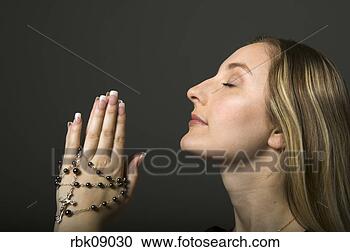 Stock Photography - young woman praying 
with rosary beads. 
fotosearch - search 
stock photos, 
pictures, images, 
and photo clipart