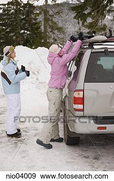 Stock Photograph - young women unloading 
snowboards from 
roof of car. fotosearch 
- search stock 
photos, pictures, 
images, and photo 
clipart