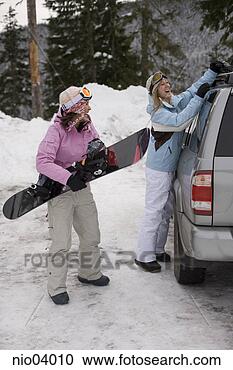 Stock Photography - young women unloading 
snowboards from 
roof of car. fotosearch 
- search stock 
photos, pictures, 
images, and photo 
clipart