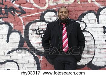Picture - african american 
businessman leaning 
against brick 
wall with graffiti. 
fotosearch - search 
stock photos, 
pictures, images, 
and photo clipart