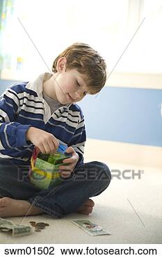 Stock Photo - boy putting money 
in coin bank. 
fotosearch - search 
stock photos, 
pictures, images, 
and photo clipart