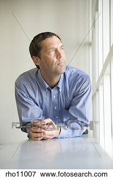Picture - businessman leaning 
on desk and staring 
out window. fotosearch 
- search stock 
photos, pictures, 
images, and photo 
clipart