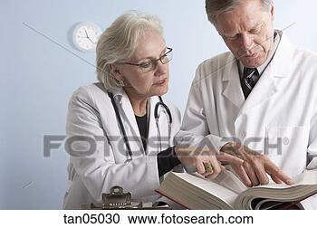Stock Photography - doctors referring 
to medical reference 
book. fotosearch 
- search stock 
photos, pictures, 
images, and photo 
clipart