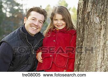Stock Image - father and daughter 
smiling near tree 
trunk. fotosearch 
- search stock 
photos, pictures, 
images, and photo 
clipart