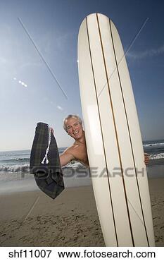 Picture - man standing naked 
behind surfboard. 
fotosearch - search 
stock photos, 
pictures, images, 
and photo clipart