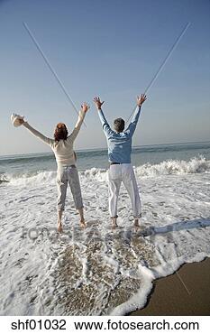 Stock Photo - mature couple 
jumping in surf 
at the beach. 
fotosearch - search 
stock photos, 
pictures, images, 
and photo clipart