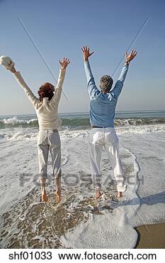 Stock Photo - mature couple 
jumping in surf 
at the beach. 
fotosearch - search 
stock photos, 
pictures, images, 
and photo clipart